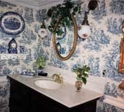Bathroom with blue and white toile wallpaper, mirror and antique vanity