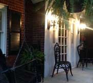Brick porch entryway with wrought iron chairs and warm evening lighting