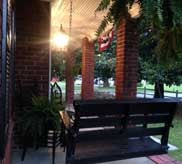 Covered porch with brick columns, a wooden bench and American flag