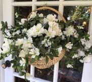 Wicker basket overflowing with white gardenias and green foliage at the front door