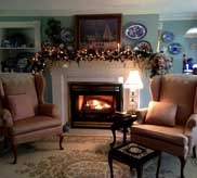 Cozy sitting room with fireplace, wingback chairs and holiday garland mantle