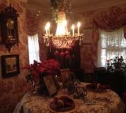 Ornate dining room with chandelier, floral wallpaper and holiday poinsettias